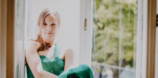 Frau mit grünem Abendkleid auf Fensterbank